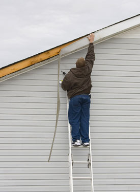 man fixing roof on ladder