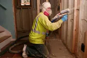 man adding foam insulation to a home